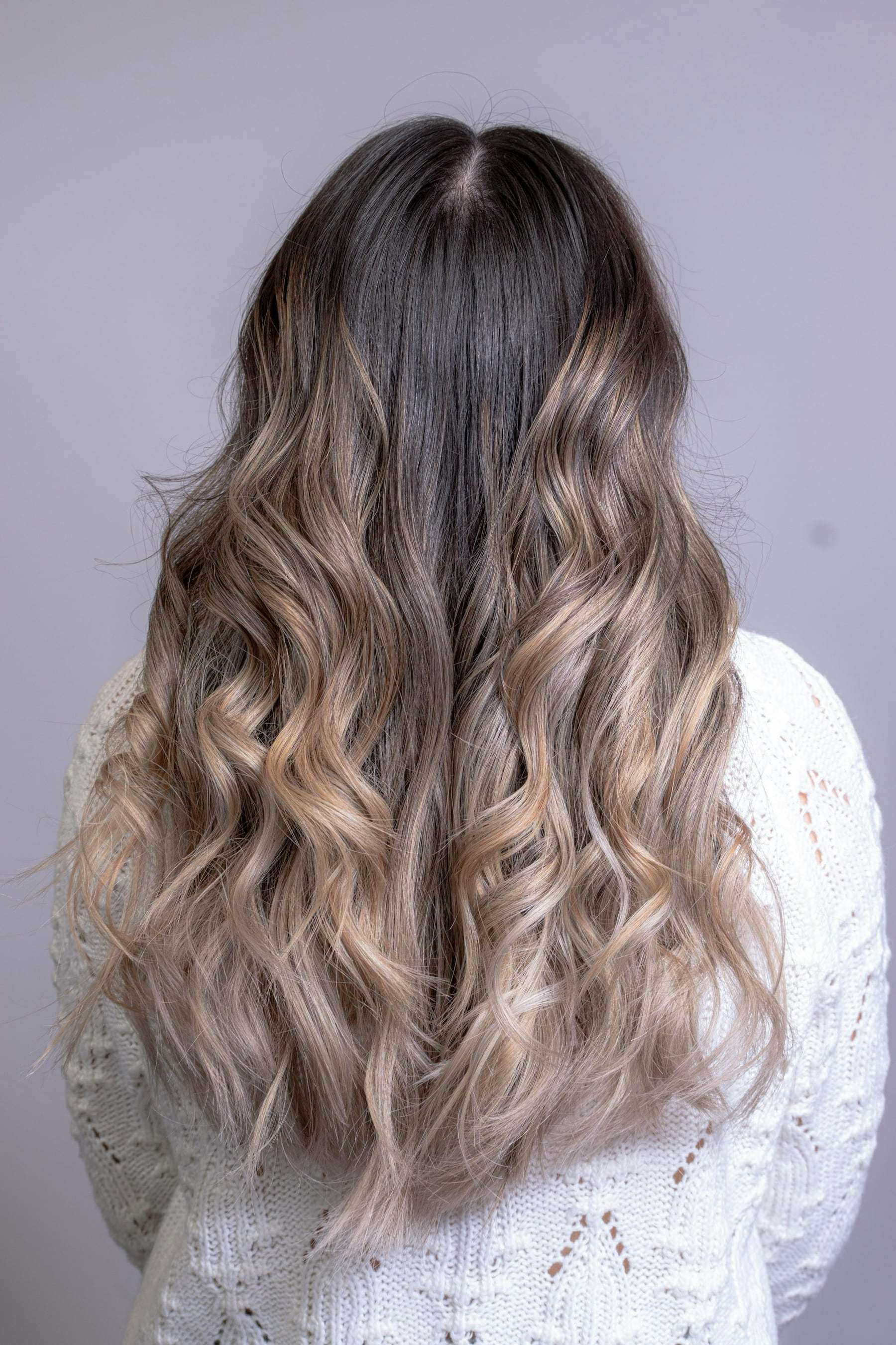 Păr lung cu balayage, de la rădăcina închisă la vârfuri blond cenușiu, văzut din spate